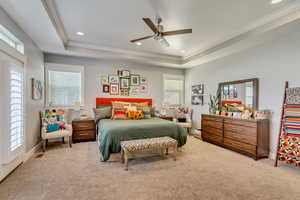 Bedroom featuring light carpet, a ceiling fan, recessed lighting, ornamental molding, and a tray ceiling