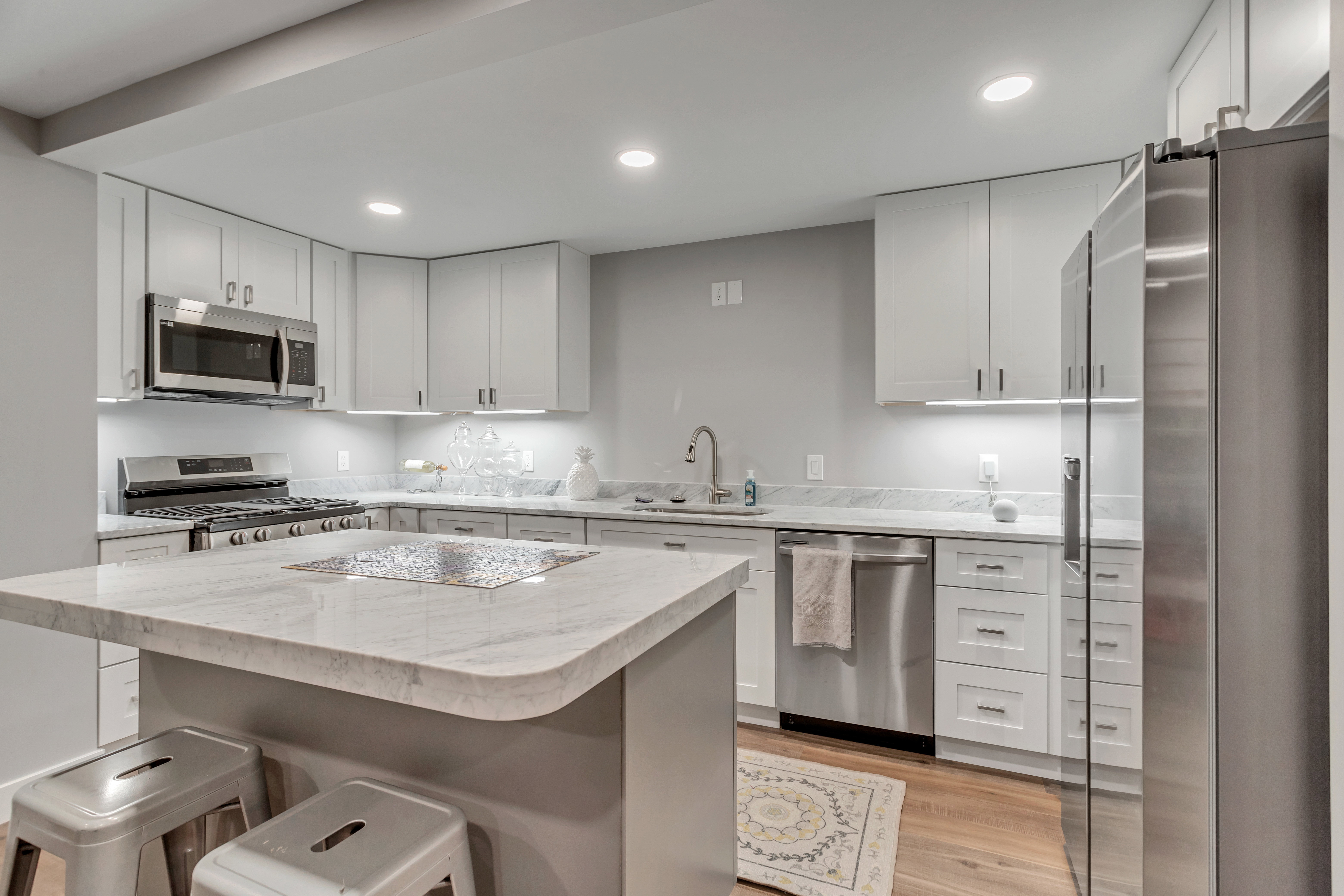 Kitchen with stainless steel appliances, light wood finished floors, white cabinetry, and recessed lighting