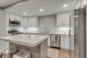 Kitchen with stainless steel appliances, light wood finished floors, white cabinetry, and recessed lighting