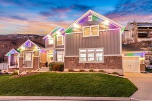 View of front of property featuring board and batten siding, a front lawn, stone siding, and driveway