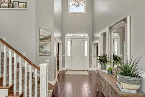 Foyer featuring dark wood-style floors, hanging lights, and a high ceiling