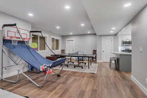 Recreation room with light wood-style flooring and recessed lighting