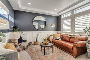 Carpeted living room featuring wainscoting, recessed lighting, ornamental molding, and a decorative wall
