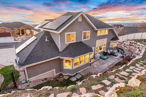 Back of house with a fenced backyard, stucco siding, solar panels, and a shingled roof