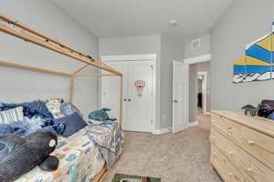 Bedroom with light colored carpet and a closet