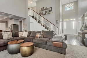 Living room with a chandelier, wood finished floors, and high coffered ceiling