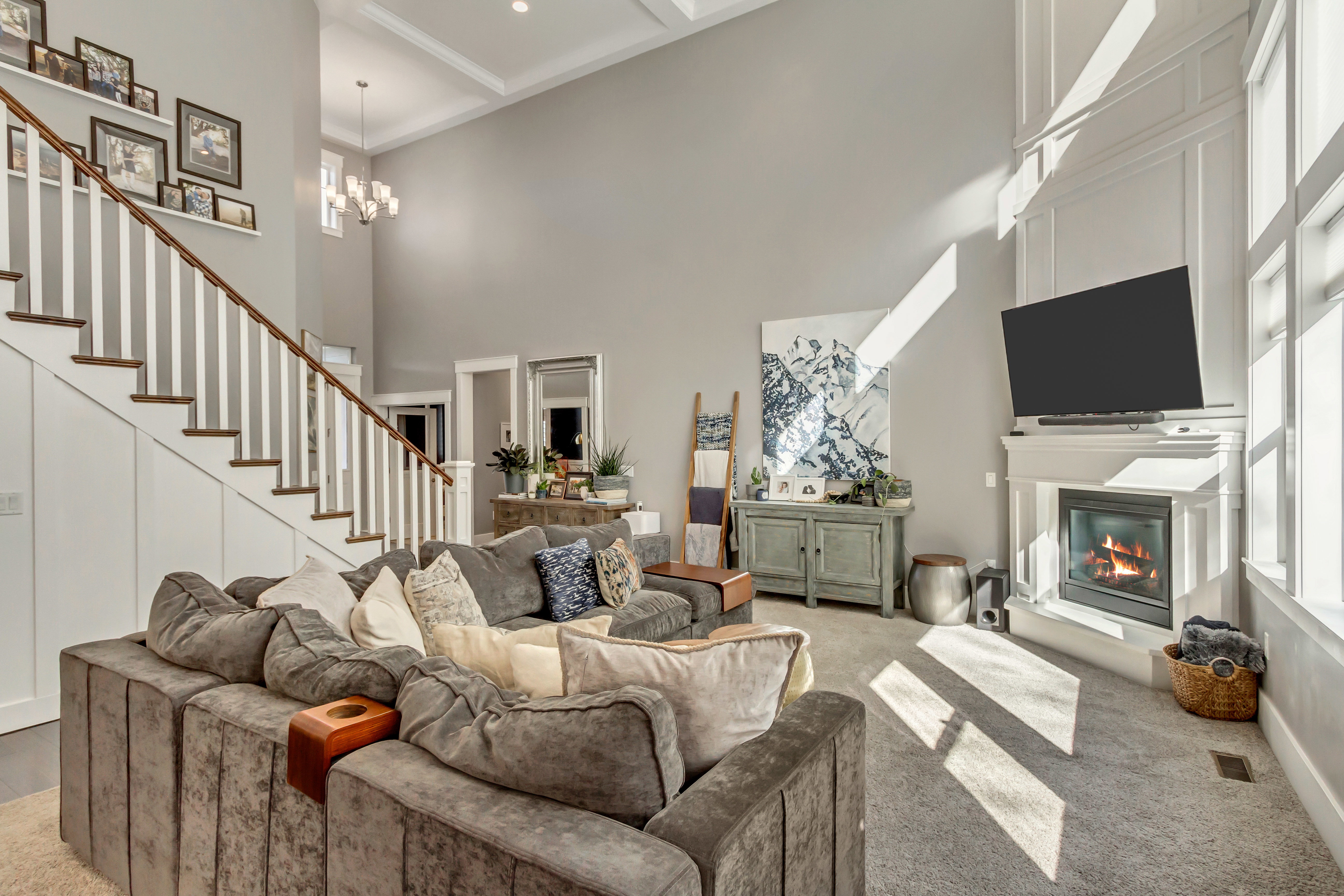 Carpeted living area featuring a glass covered fireplace, suspended lighting, and a high ceiling