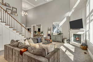 Carpeted living area featuring a glass covered fireplace, suspended lighting, and a high ceiling