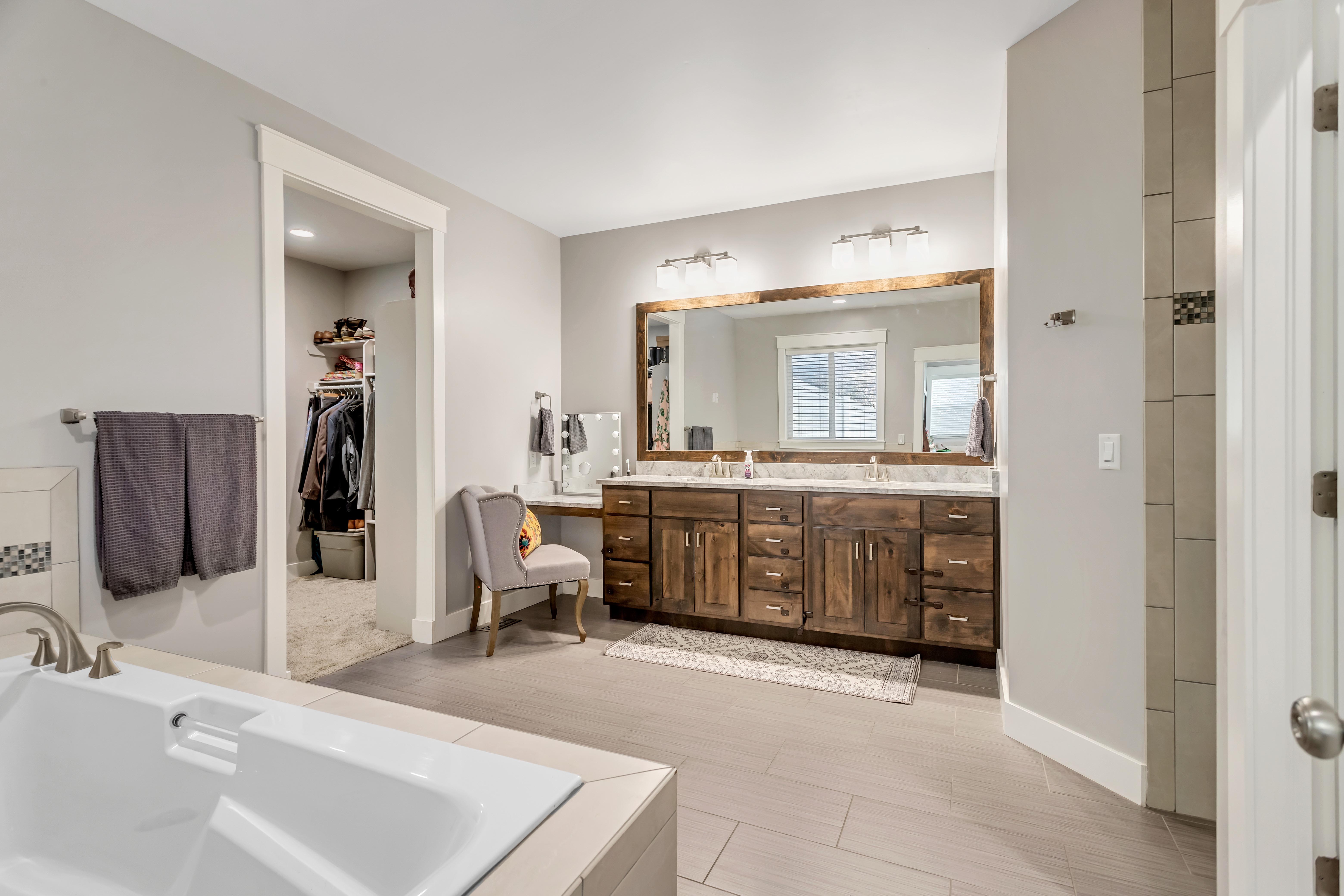 Bathroom featuring a bath, double vanity, and a walk in closet