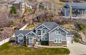 Craftsman inspired home with concrete driveway, stone siding, board and batten siding, an attached garage, and a shingled roof