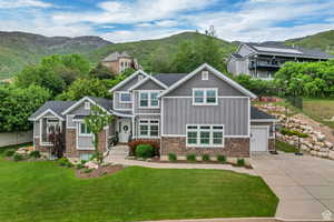 Craftsman-style home featuring a mountain view, board and batten siding, stone siding, driveway, and an attached garage