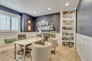 Office with a wainscoted wall, a decorative wall, built in shelves, light colored carpet, and recessed lighting
