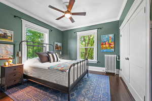 Bedroom with radiator, dark wood finished floors, a ceiling fan, and crown molding