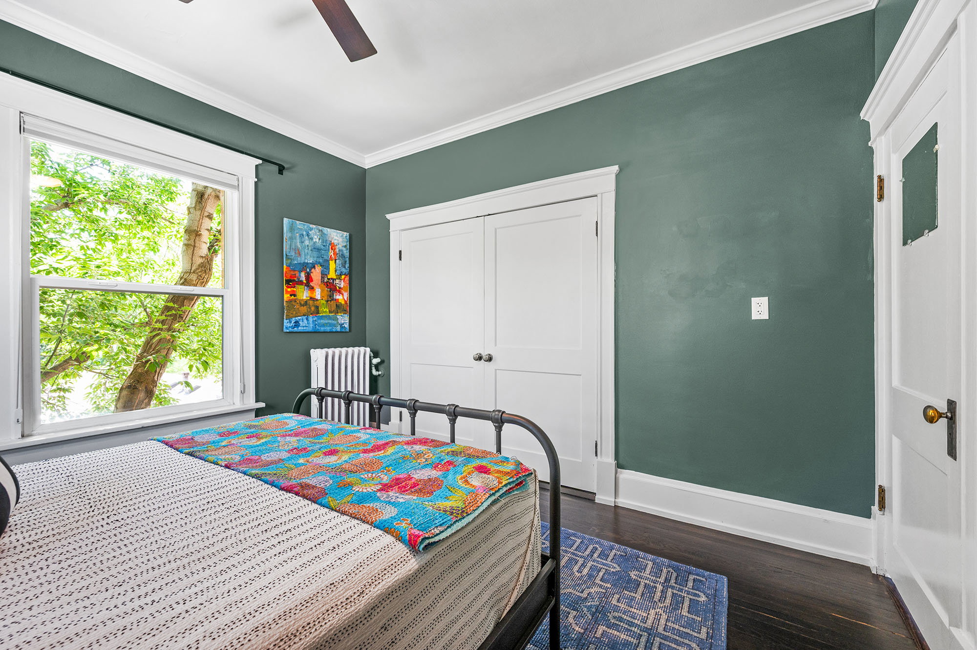 Bedroom with ornamental molding, dark wood finished floors, a closet, radiator heating unit, and ceiling fan