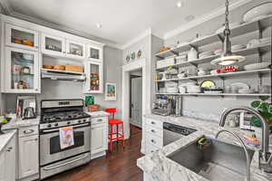 Kitchen with stainless steel appliances, ornamental molding, white cabinetry, open shelves, and dark wood-type flooring