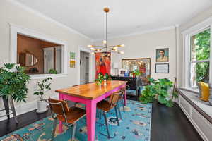 Dining area with dark wood finished floors, a chandelier, and crown molding