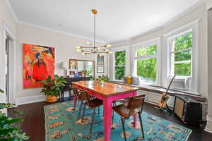 Dining area with a chandelier, dark wood-type flooring, and ornamental molding