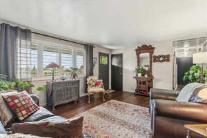 Living room with hardwood flooring and large newer windows.