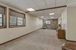 Below grade area featuring a paneled ceiling, a textured wall, and carpet flooring