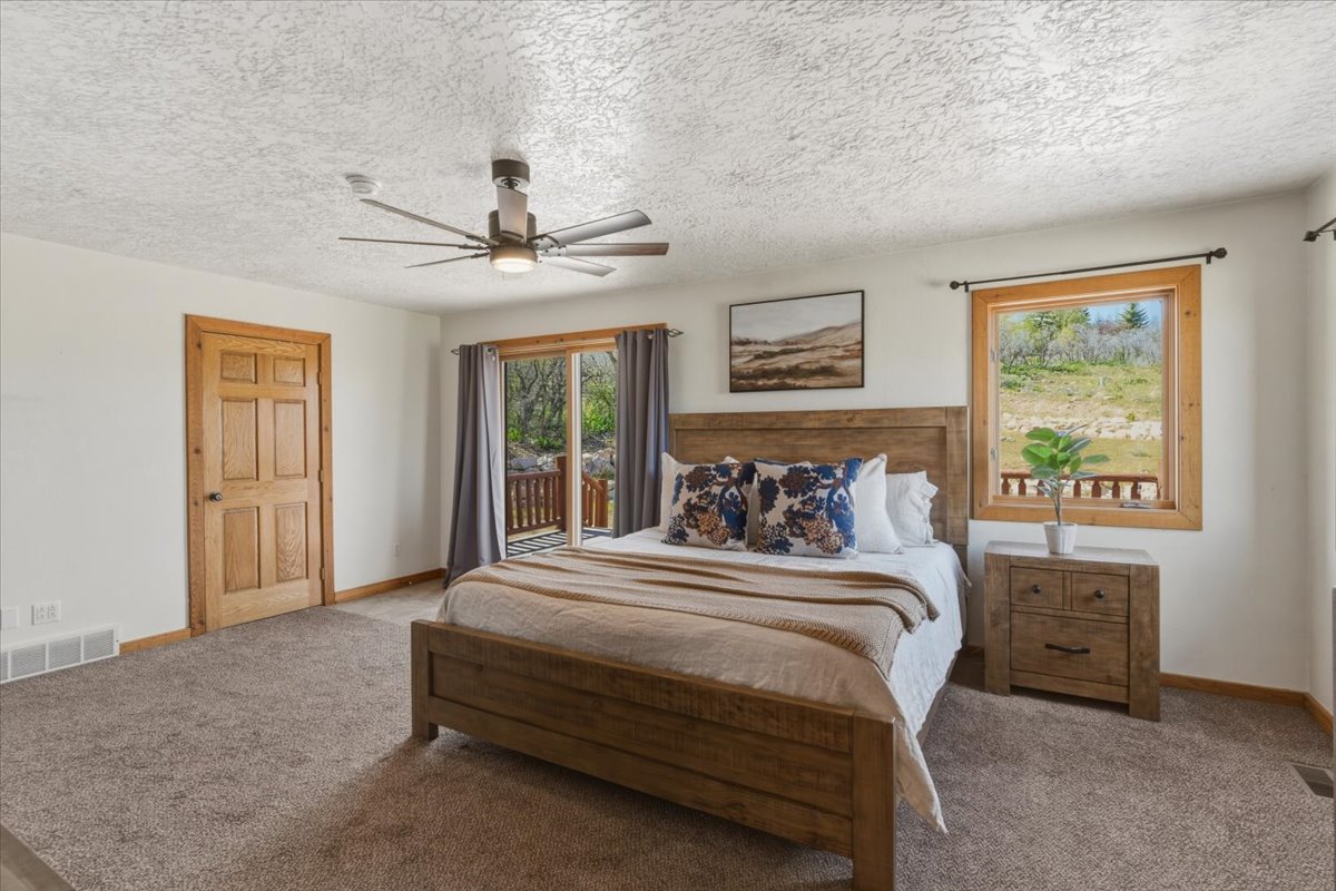 Carpeted bedroom featuring access to exterior, a textured ceiling, and ceiling fan