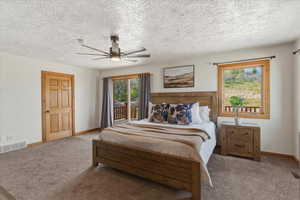 Carpeted bedroom featuring access to exterior, a textured ceiling, and ceiling fan