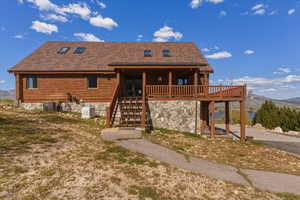 View of front of property featuring a mountain view, covered porch, log exterior, and a shingled roof