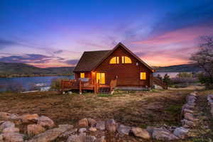 Back of property featuring a deck with water view and log siding