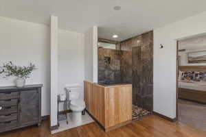 Ensuite bathroom with walk in shower, wood finished floors, and a textured ceiling