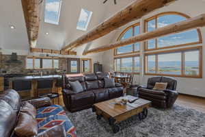Living area with lofted ceiling, wood finished floors, a mountain view, and a skylight
