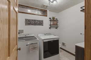 Laundry area featuring a textured ceiling and washer and clothes dryer