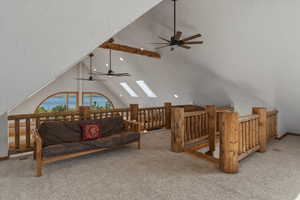 Living room with ceiling fan, light colored carpet, and a skylight