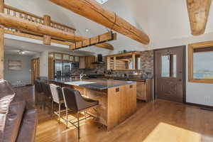 Kitchen featuring wood finish cabinetry, a kitchen breakfast bar, light wood-style flooring, stainless steel appliances, and lofted ceiling