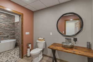 Full bathroom featuring a freestanding bath, a drop ceiling, vanity, and light wood-type flooring