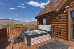 Deck with a hot tub and a water and mountain view