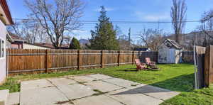 Fenced backyard featuring a shed and a patio area