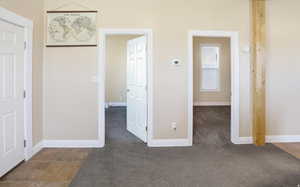 Unfurnished bedroom featuring dark carpet and baseboards