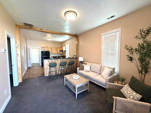 Living area with dark colored carpet and a textured ceiling