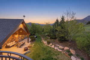 View of grassy yard featuring a patio area, a mountain view, and an outdoor living space with a fire pit