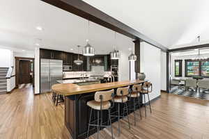 Kitchen with a breakfast bar, wood counters, a peninsula, stainless steel appliances, and light wood-style floors