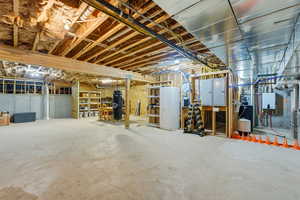 Unfinished below grade area with electric panel and water heater