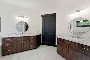 Bathroom featuring two vanities and light marble finish floors