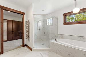 Bathroom with a towel warming rack, a marble finish shower, a garden tub, light marble finish flooring, and radiator