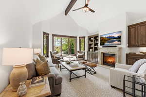 Living area with ceiling fan, a fireplace, and built in shelves