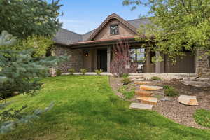 View of front of home with a front yard, a shingled roof, and a patio area