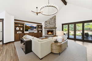 Living room featuring light wood-style flooring, a brick fireplace, hanging lights, and built in shelves