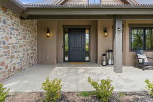 View of exterior entry with stone siding and a porch