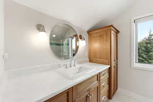 Full bathroom with vanity, a shower stall, and lofted ceiling