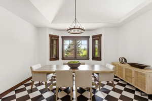 Dining room with dark floors, a chandelier, a raised ceiling, and lofted ceiling