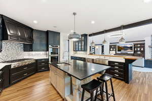Kitchen with a kitchen breakfast bar, a peninsula, decorative light fixtures, open floor plan, and glass fronted cabinets
