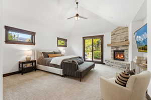 Bedroom with light carpet, access to exterior, a fireplace, ceiling fan, and lofted ceiling
